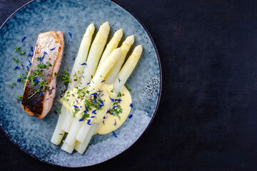 Traditionell gedämpfter weißer Spargel mit Lachs Filet und Sauce Hollandaise serviert als...