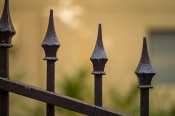 Spear Tipped Black Metal Gate with a Yellow Background.