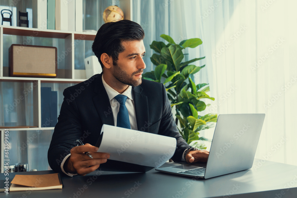 Poster modern professional businessman at modern office desk using laptop to work and write notes. diligent