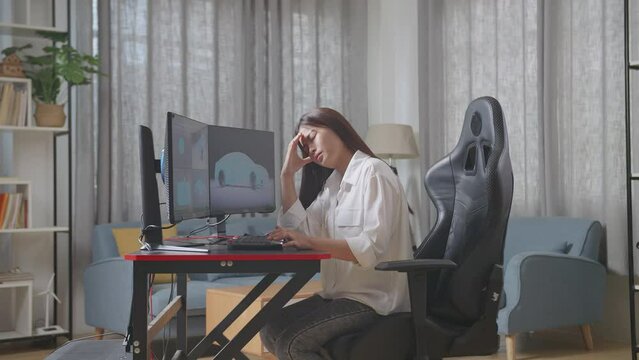 Side View Of Asian Female Automotive Designer Shaking Her Head Being Tired Working On 3D Model Of Ev Car On The Desktop Computers In The Studio

