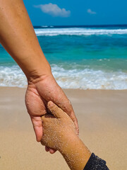 Close up view of father and son holding hand on the beach. Family trust, support and care concept
