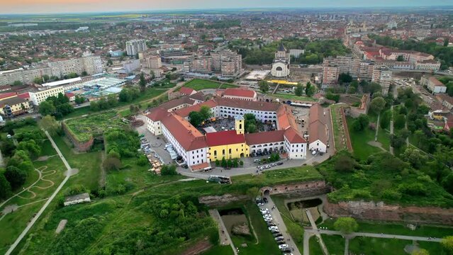 Aerial drone view of Oradea Fortress at sunset, Romania. Multiple people inside the fortress, residential district with multiple buildings around