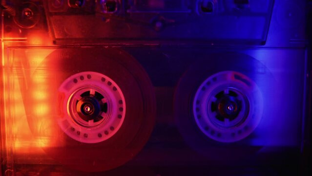 Vintage cassette recorder roller. Audio reel tape is rotating at an old school professional player. Retro night club disco party or synthwave aesthetics concept. DJ remix or mixtape purple background
