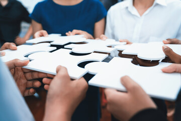 Diverse corporate officer workers collaborate in office, connecting puzzle pieces to represent...