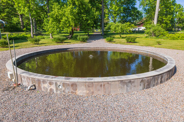 Close up view of garden landscape design with round decorative outdoor pond with fishes. Sweden.