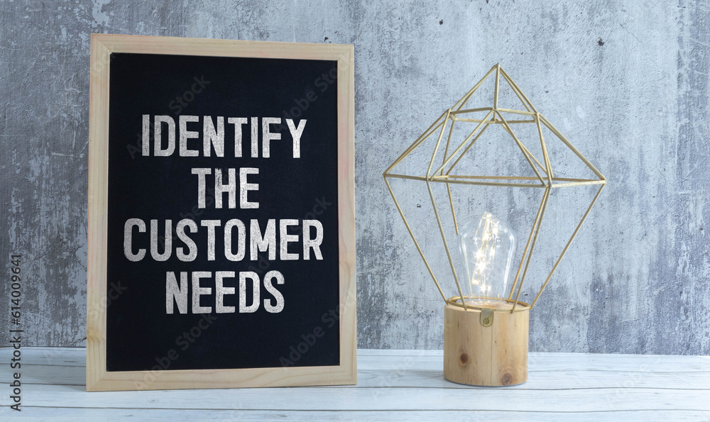 Poster notepad with identify the customer need text on keyboard with felt-tip pens and calculator on wooden