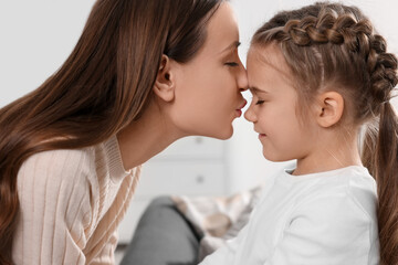Happy mother kissing her cute daughter indoors, closeup