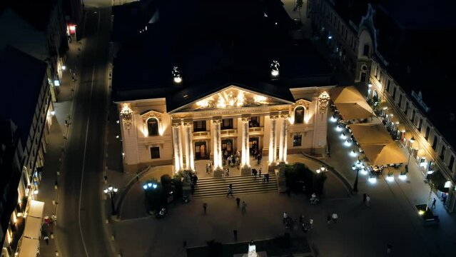 Aerial drone view of Oradea downtown at night, Romania. State Theatre with people coming out, illumination