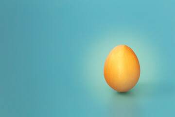 Golden egg isolate on blue background. Copy space. Horizontal.