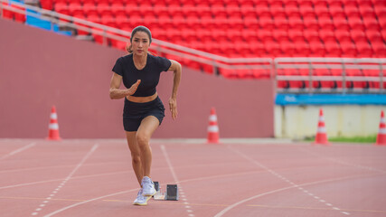 Asian female athlete accelerates during her speed running practice on the stadium track, embodying determination