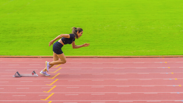 Asian female athlete accelerates during her speed running practice on the stadium track, embodying determination