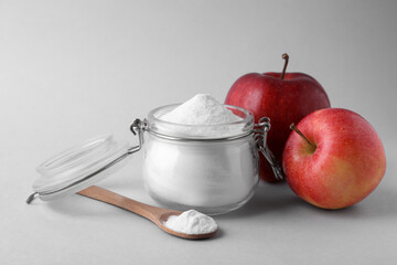 Jar, spoon with sweet fructose powder and ripe apples on white background