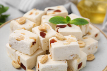 Pieces of delicious nutty nougat on plate, closeup