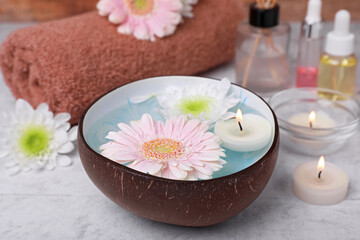 Obraz na płótnie Canvas Beautiful composition with bowl of water, flowers and candles on light table, closeup. Spa treatment