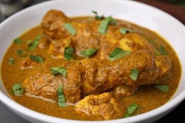 Delicious chicken with curry sauce in bowl, closeup
