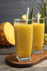 Tasty pineapple smoothie and cut fruit on wooden table