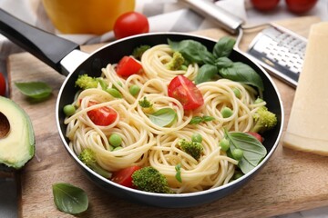 Delicious pasta primavera in frying pan and ingredients on table, closeup