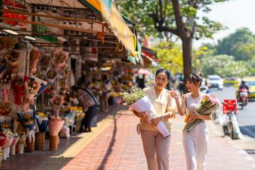 Happy Asian family mother and daughter holding flower bouquet walking together during shopping at...