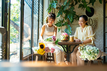 Happy Asian mother and daughter sitting in coffee shop with drinking coffee and eating cake together. Happy family enjoy outdoor lifestyle travel and shopping in the city on summer holiday vacation.