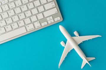 Airplane model and computer keyboard on blue background. Booking flight airways tickets online concept. Search easy best flight, plan, compare lowest and cheap air fare tickets, deal.