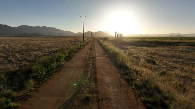 POV shot of driving down a rural dirt road into the sun