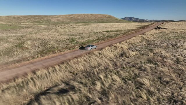 Drone shot of car driving on dirt road in Willcox, Arizona, tracking aerial shot drone moves behind car