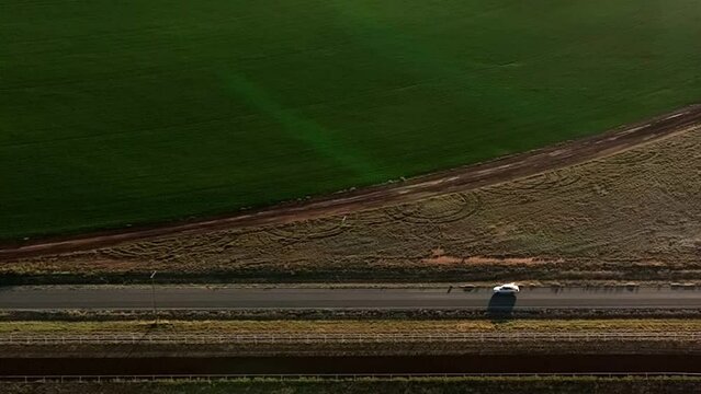 Aerial shot of car driving on dirt road in near pivots with green farm growth in Willcox, Arizona, wide side angle drone shot