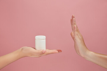 One hand acting like they are rejecting the medicine bottle in white color. Some medicines relieve pain. Hand models concept