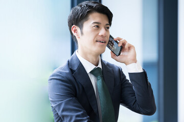 Handsome young Asian businessman on the phone in his office