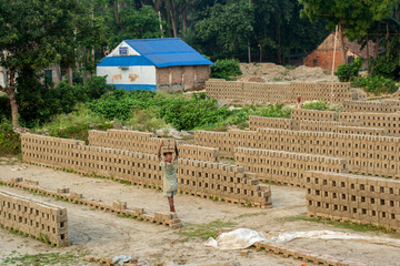 Fototapeta na wymiar 5th June, 2023, Burul, West Bengal, India: Blocks of hand made traditional bricks stack under the sun to dry up in a brick factory.