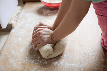 Female kneading the flour dough by hand on chopping board.