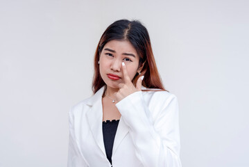 A sarcastic young woman pulling her lower eyelid with a finger to mock someone. Isolated on a white...