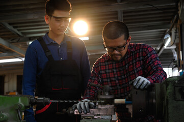 Fototapeta na wymiar Asian apprentice young engineer discussion with technician on the job, Studying machine maintenance for drilling holes in wood. Skill in the working job of mechanical engineering concept.