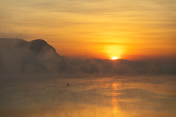 Sunrise on Hartbeespoort Dam Reservoir in South Africa with standing paddler tourist as mist rises from the water