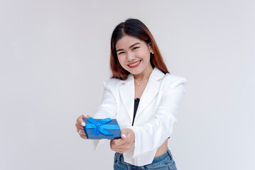 A happy and smiling young woman holding a small blue gift while smiling at the camera. Isolated on a white background.
