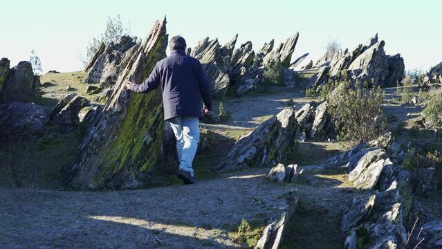 Hiking man resting in a strange landscape full of sharp rocks in the Sierra del Rincon, Madrid.