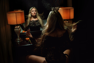 Portrait of blonde woman in black guipure lingerie looking in mirror