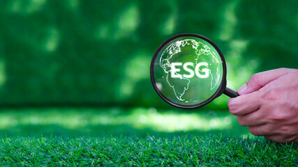 ESG concept of environmental, social and governance. Hand holding magnifying glass with ESG and...