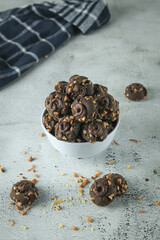 Kue coklat or Chocolate cookies or choco button cookies for Lebaran. Made from butter, egg, dark cooking chocolate, flour, cocoa pwder and cashew nut. served in grey and texture background