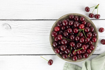 Plate of fresh red cherries on white background. Top view. Copy space.