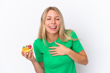 Young caucasian woman holding a tartlet isolated on white background smiling a lot