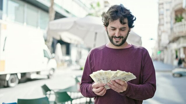 Young hispanic man counting denmark krone banknotes at coffee shop terrace