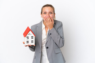 Real estate agent woman holding a toy house isolated on white background happy and smiling covering mouth with hand