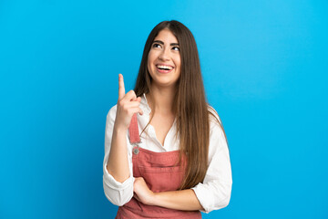 Young caucasian woman isolated on blue background pointing up and surprised