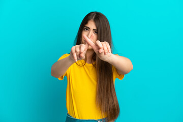 Young caucasian woman isolated on blue background making stop gesture with her hand to stop an act