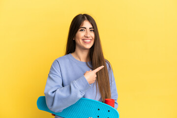 Young caucasian woman isolated on yellow background with a skate and pointing to the side