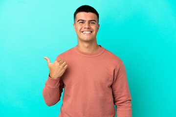 Young handsome man over isolated blue background pointing to the side to present a product