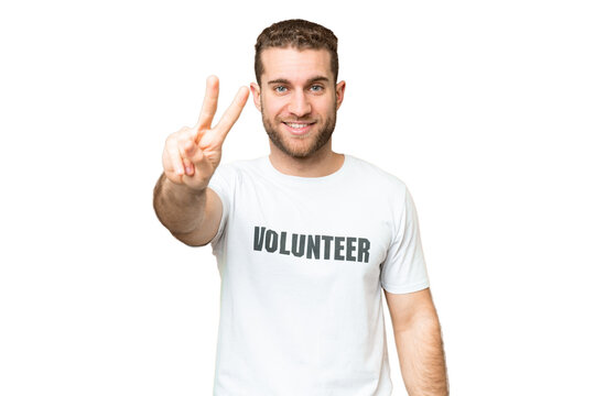 Young volunteer man over isolated chroma key background smiling and showing victory sign