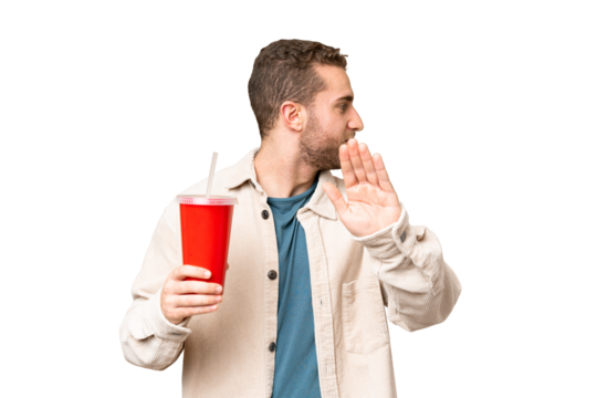 Young handsome blonde man holding soda over isolated chroma key background making stop gesture and disappointed