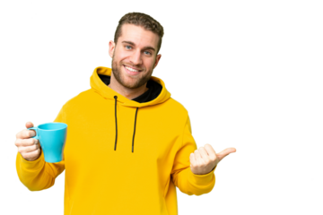 Young handsome blonde man holding cup of coffee over isolated background pointing to the side to present a product